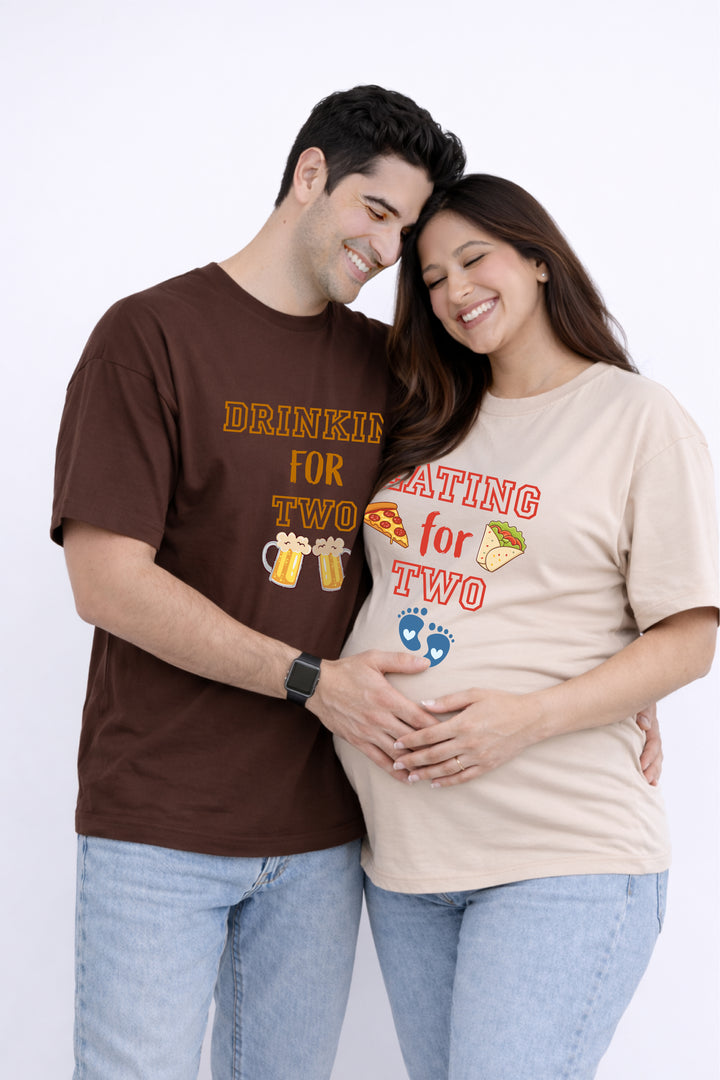 Man and woman wearing matching t-shirts with pregnancy announcements on a white background